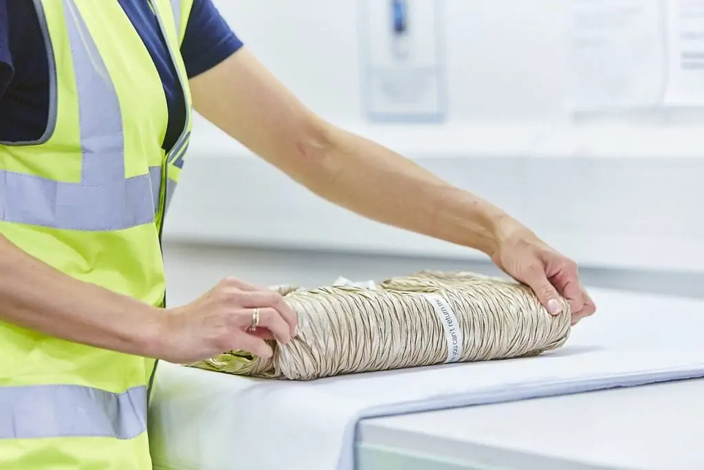 Gift wrapping fulfilment service - a woman carefully wraps a gold dress