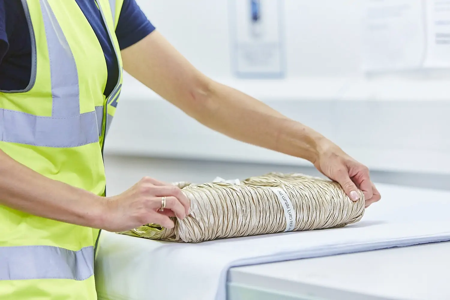 Gift wrapping fulfilment service - a woman carefully wraps a gold dress