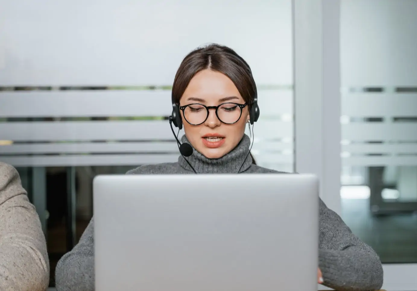 Women with headset on sitting in front of a laptop, talking