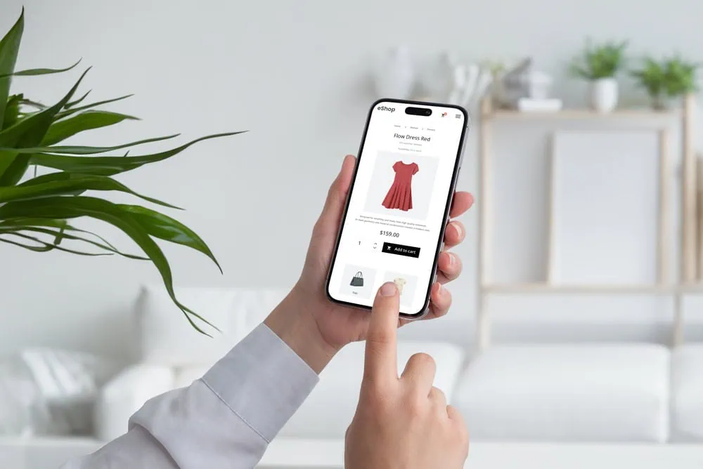 hands holding an iPhone showing checkout screen of an e-commerce fashion website