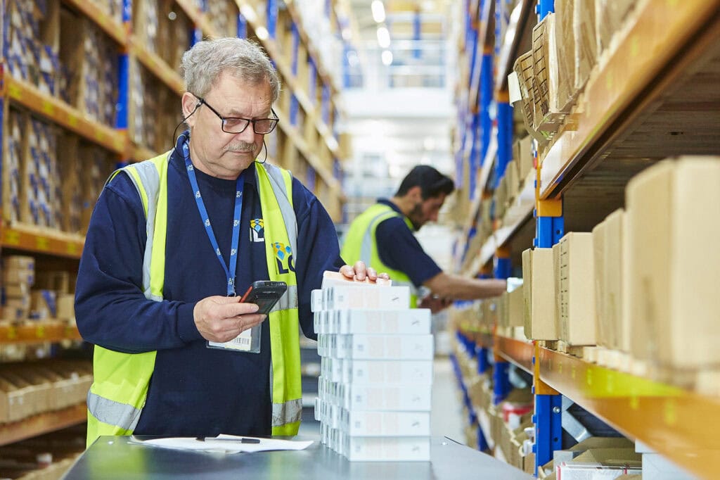 man scanning boxes in warehouse aisle